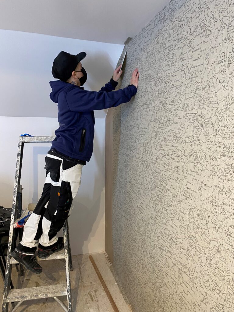 Etudiant posant une tapisserie sur un mur